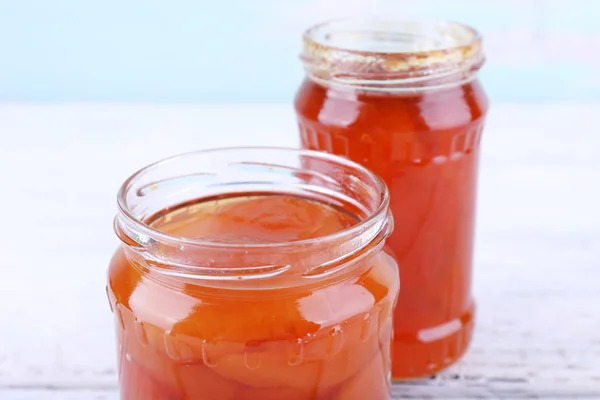 Vasi fatti in casa di marmellata di frutta su tavolo di legno e sfondo della parete di colore — Foto Stock