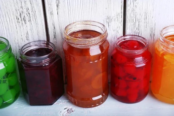 Hausgemachte Gläser mit Obst Marmelade auf dem Tisch und Farbe Holzplanken Hintergrund — Stockfoto