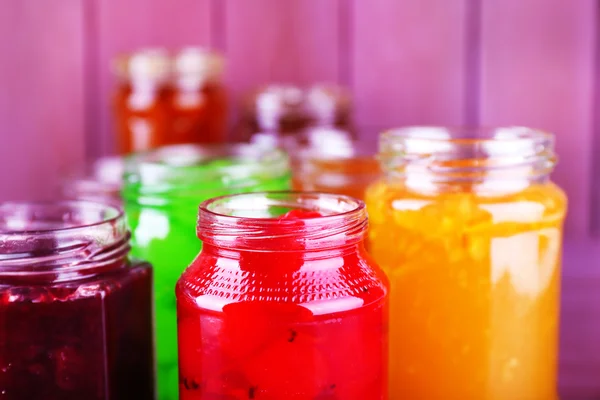 Homemade jars of fruits jam on color wooden background — Stock Photo, Image