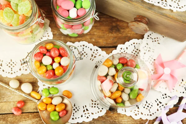 Caramelos multicolores en frascos de vidrio sobre fondo de madera —  Fotos de Stock
