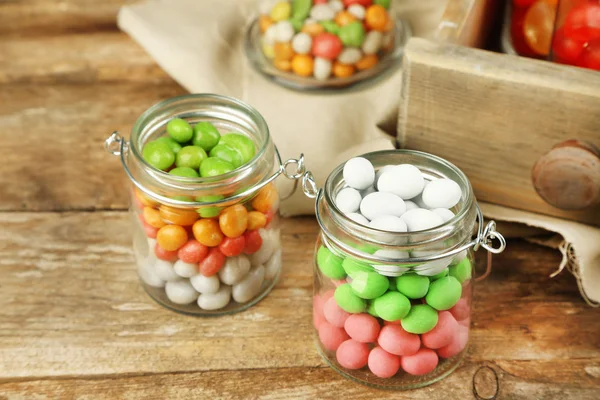 Caramelos multicolores en frascos de vidrio sobre fondo de madera —  Fotos de Stock