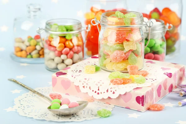 Bonbons multicolores dans des pots en verre sur fond coloré — Photo