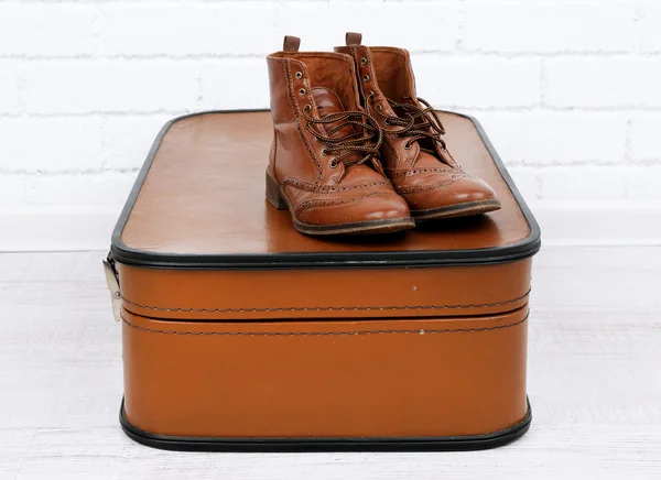 Vintage-Koffer mit Männerschuhen auf Holzboden und Backsteinmauer — Stockfoto