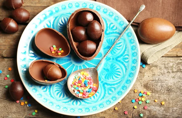Chocolate Easter eggs on color plate, on wooden background — Stock Photo, Image