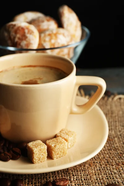 Kopp kaffe och välsmakande kakor på säckväv Servett, på träbord, på mörk bakgrund — Stockfoto