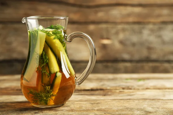 Glass ewer with fresh organic cucumber water on wooden table — Stock Photo, Image