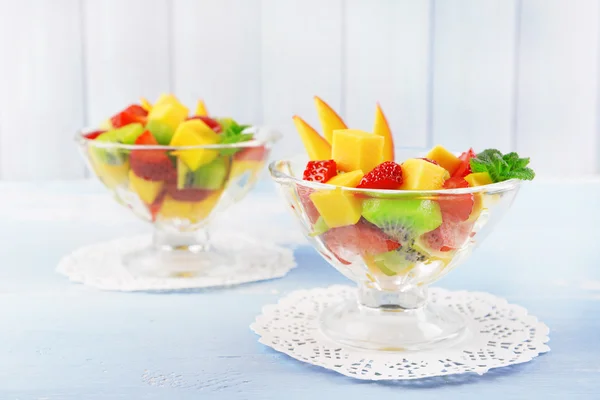 Fruitsalade met muntblaadjes in glaswerk op houten tafel en planken achtergrond — Stockfoto