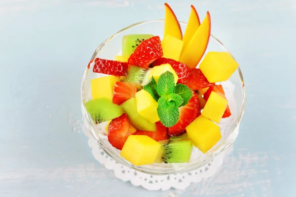 Salada de frutas em tigela de vidro com hortelã sobre fundo de madeira cor — Fotografia de Stock