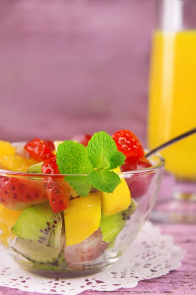 Insalata di frutta con menta e succo d'arancia in bicchieri su sfondo di legno a colori — Foto Stock