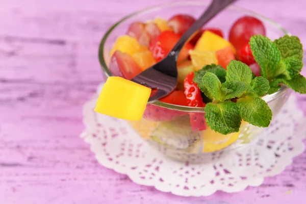 Фруктовый салат с мятой в стеклянной посуде на фоне цвета дерева — стоковое фото