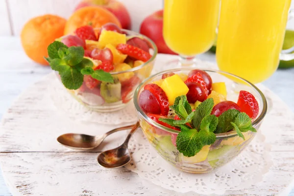 Insalata di frutta con menta e succo d'arancia in bicchieri su sfondo di legno a colori — Foto Stock