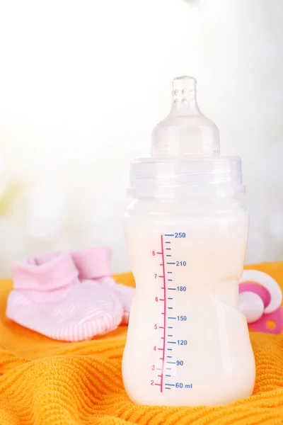 Bottiglia di latte per bambini, ciuccio e babys bootee su sfondo giallo — Foto Stock