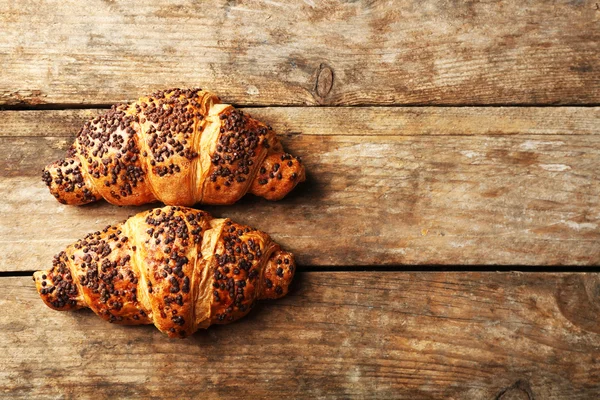 Croissants frescos e saborosos com chocolate em fundo de madeira — Fotografia de Stock