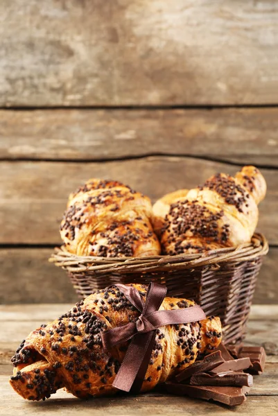 Croissant freschi e gustosi con cioccolato su sfondo di legno — Foto Stock