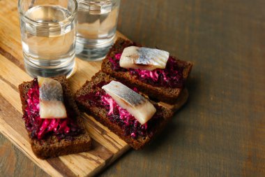 Kanepe ringa pancar üzerinde ahşap tahta ve bardak votka ahşap masa arka plan üzerinde çavdar tost ile