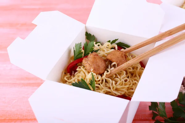 Macarrão chinês com carne e pimenta em caixa takeaway no fundo rosa — Fotografia de Stock