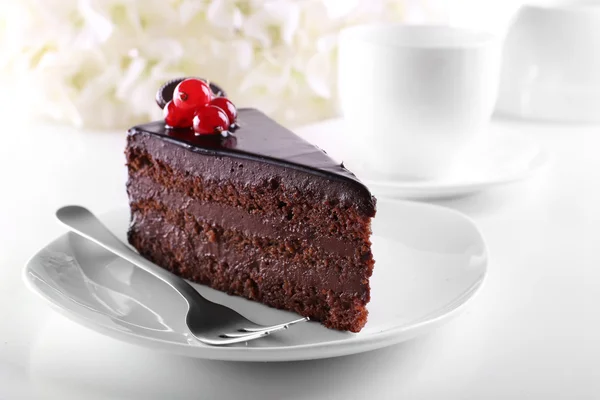 Delicious chocolate cake on plate on table on light background — Stock Photo, Image