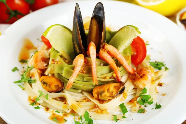 Tasty pasta with shrimps, mussels, tomatoes on plate close-up — Stock Photo, Image