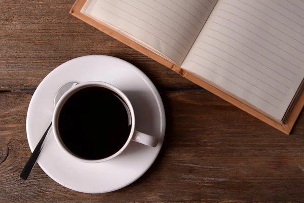 Kopp kaffe på fat med bärbara och sked på träbord bakgrund — Stockfoto