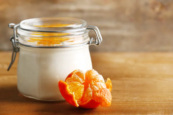 Tasty milk dessert with fresh tangerine pieces in glass jar, on  wooden background — Stock Photo, Image