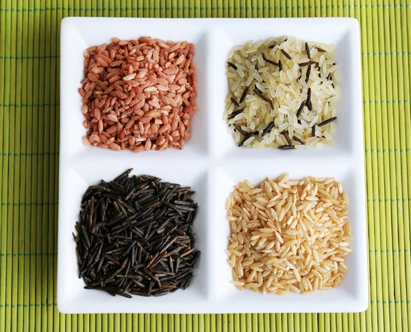 Diferentes tipos de arroz en plato sobre fondo de bambú — Foto de Stock