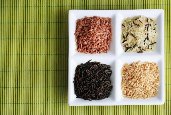 Diferentes tipos de arroz en plato sobre fondo de bambú — Foto de Stock