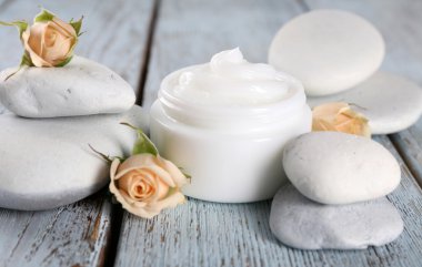 Çiçek ve spa taşlar ahşap arka plan üzerinde kozmetik krem