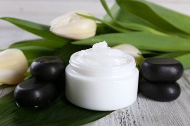 Çiçek ve spa taşlar ahşap arka plan üzerinde kozmetik krem