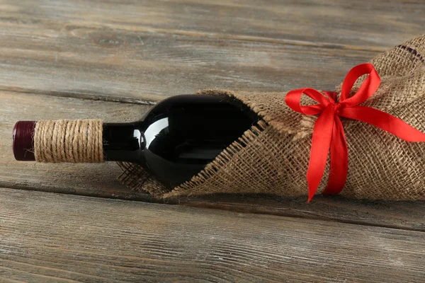 Bouteille de vin rouge enveloppée dans un tissu de toile de jute — Photo