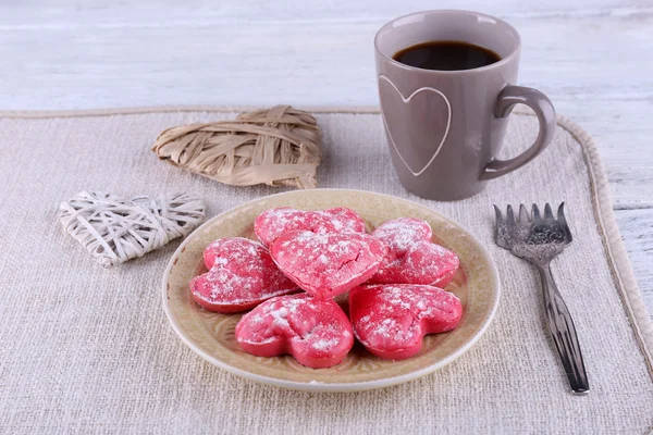 ナプキンと色の木板背景にコーヒーのカップと皿の上のハートの形のクッキー — ストック写真