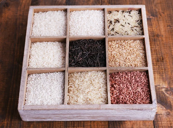 Diferentes tipos de arroz en caja sobre fondo de madera — Foto de Stock