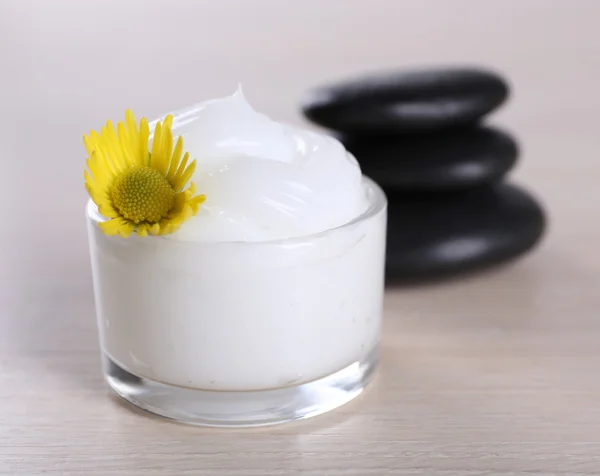 Cosmetic cream with spa stones and chamomile on wooden background — Stock Photo, Image