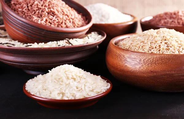 Diferentes tipos de arroz em tigelas em fundo de madeira — Fotografia de Stock