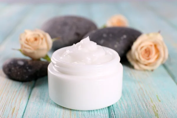 Crème cosmétique aux fleurs et pierres de spa sur fond de bois — Photo