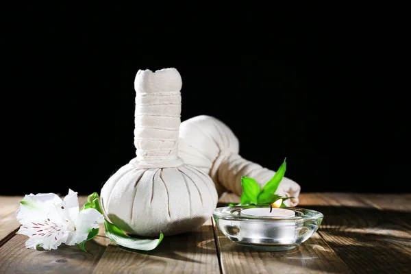 Bela composição com sacos de massagem e vela na mesa sobre fundo escuro — Fotografia de Stock