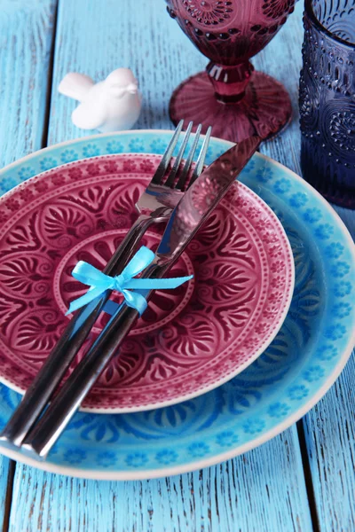 Lege kleurrijke borden, glazen en zilverwerk op houten tafel — Stockfoto