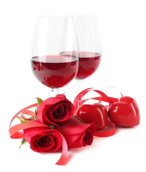 Composition with red wine in glasses, red roses, ribbon and decorative hearts isolated on white Royalty Free Stock Images