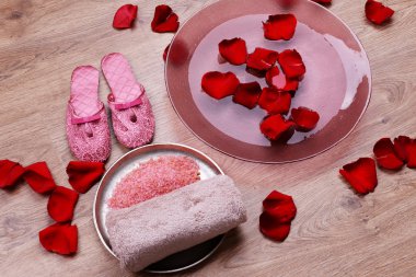 Spa kaseyle su, gül yaprakları, havlu ve terlik ışık arka plan üzerinde. Pedikür veya doğal kaplıca tedavisi kavramı