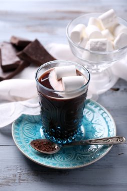 Sıcak çikolata şekerleme cam, renkli ahşap arka plan üzerinde