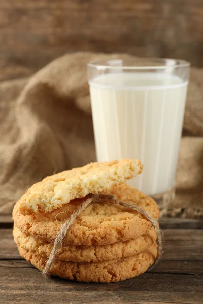 Sabrosas galletas y vaso de leche sobre fondo rústico de madera —  Fotos de Stock