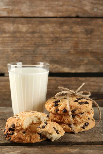 Sabrosas galletas y vaso de leche sobre fondo rústico de madera — Foto de Stock