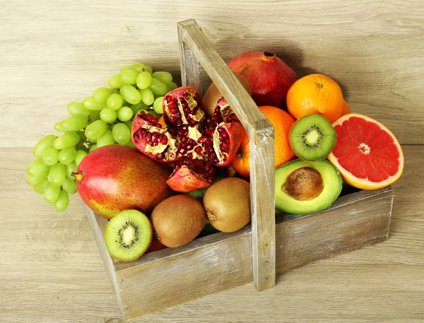 Assortiment exotisch fruit in doos op houten ondergrond — Stockfoto