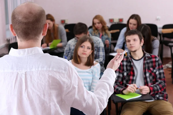 Groupe d'étudiants assis en classe et enseignant à l'écoute — Photo