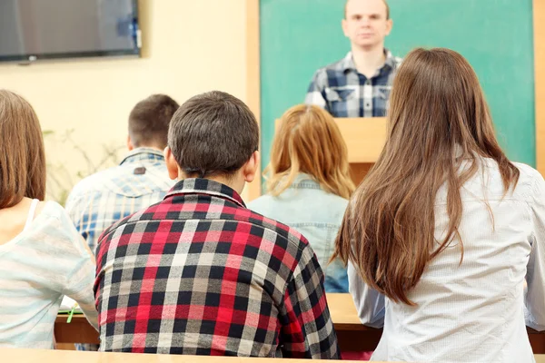 Groep van studenten in de klas zitten en luisteren leraar — Stockfoto