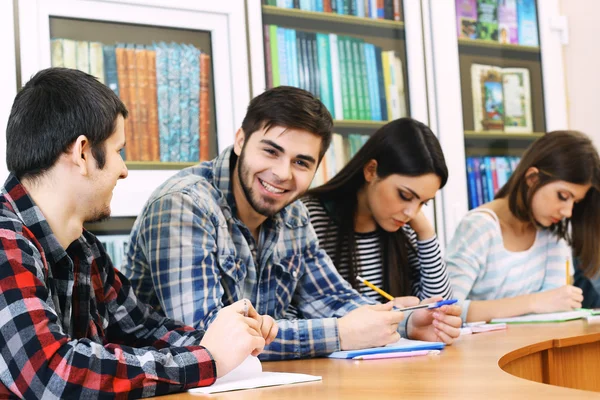 Grupa studentów siedząca przy stole w bibliotece — Zdjęcie stockowe