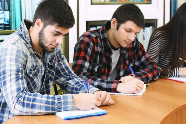 Gruppo di studenti seduti a tavola in biblioteca — Foto Stock