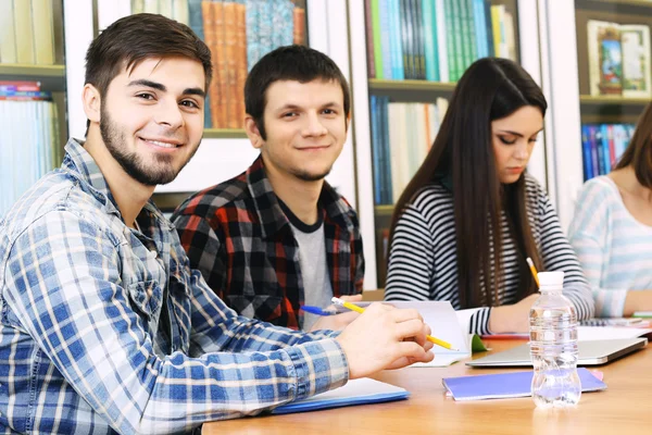 Grupo de estudantes sentados à mesa na biblioteca — Fotografia de Stock