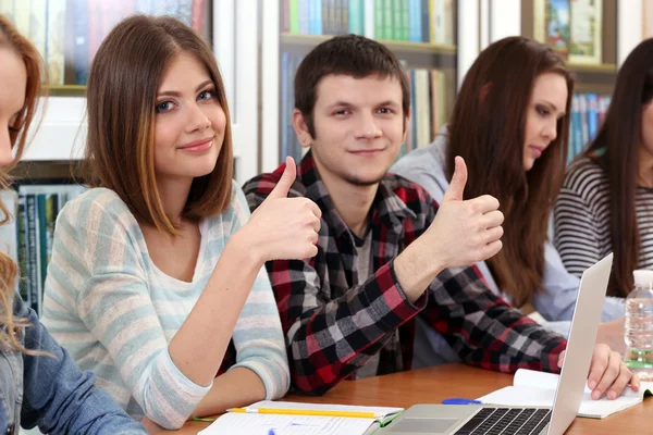 Grupo de estudantes sentados à mesa na biblioteca — Fotografia de Stock