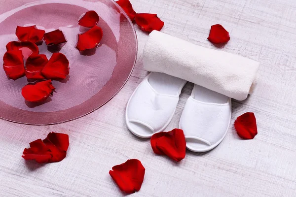 Cuenco spa con agua, pétalos de rosa, toalla y zapatillas sobre fondo claro. Concepto de pedicura o tratamiento de spa natural — Foto de Stock