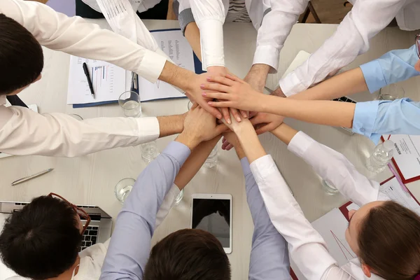 Verenigd handen van zakelijke team op werkruimte achtergrond bovenaanzicht — Stockfoto